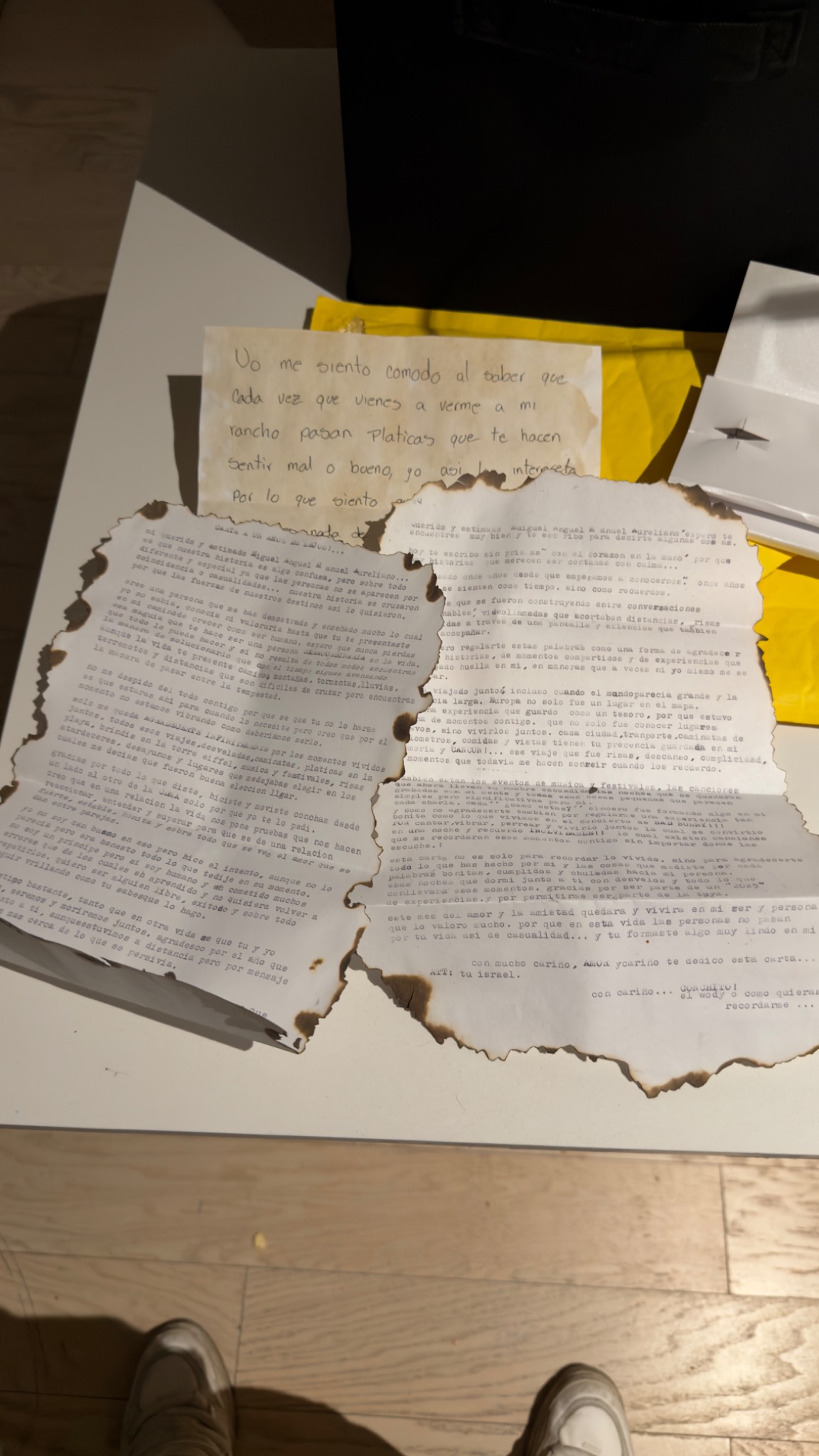 Carta de despedida con bordes quemados sobre un sobre amarillo